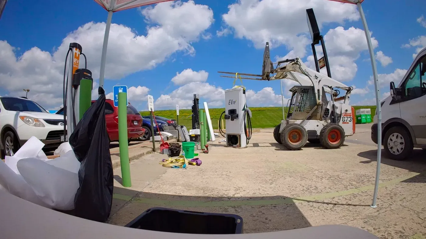 Skid steer setting an EVre DC fast charger cabinet during installation at an active site